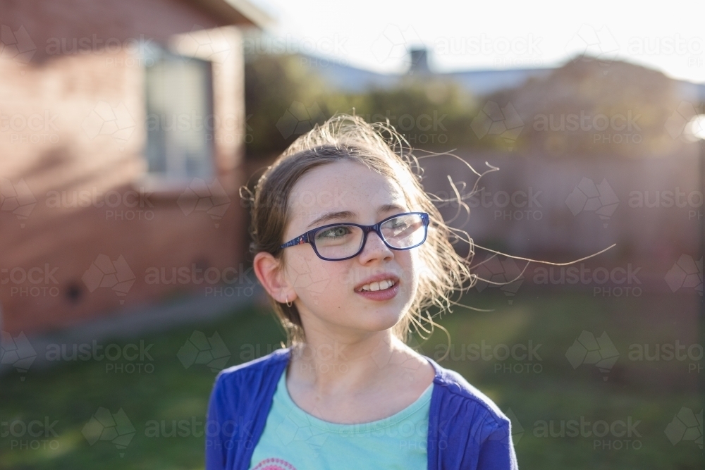 Girl wearing glasses standing in afternoon sun - Australian Stock Image