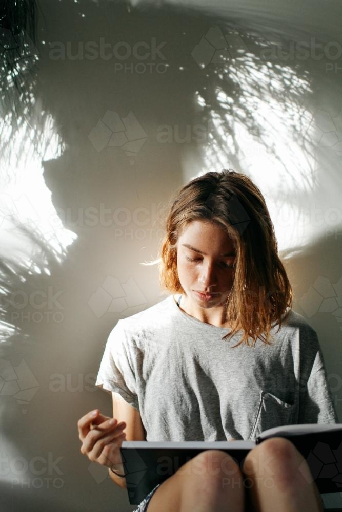 Girl with book and pencil in afternoon light - Australian Stock Image