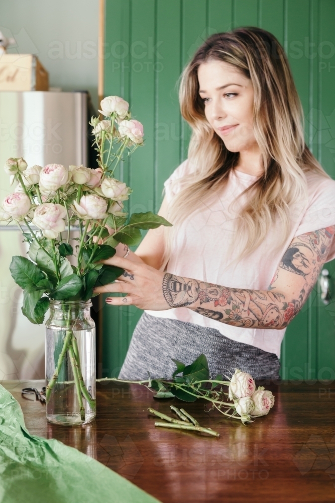 Girl with cute arm tattoos arranging pretty pink roses - Australian Stock Image