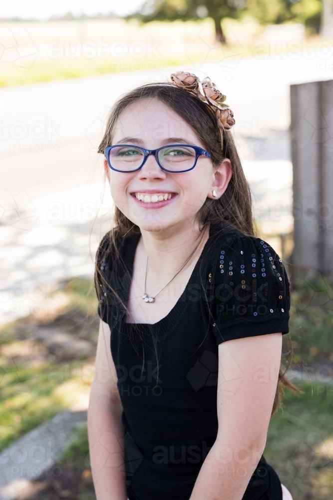 Girl with glasses smiling wearing headband - Australian Stock Image