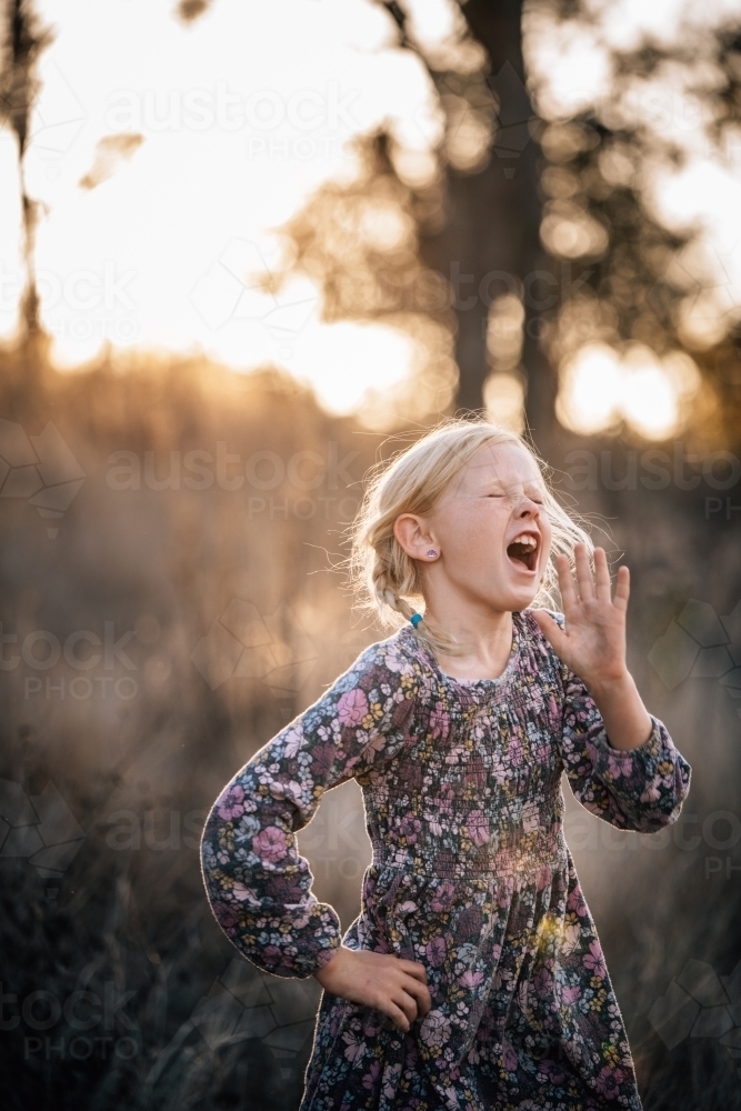 Girl with her hand upto her face singing into the distance - Australian Stock Image