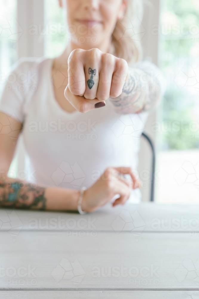 Girl with tattoos showing fist to camera in a powerful punch - Australian Stock Image