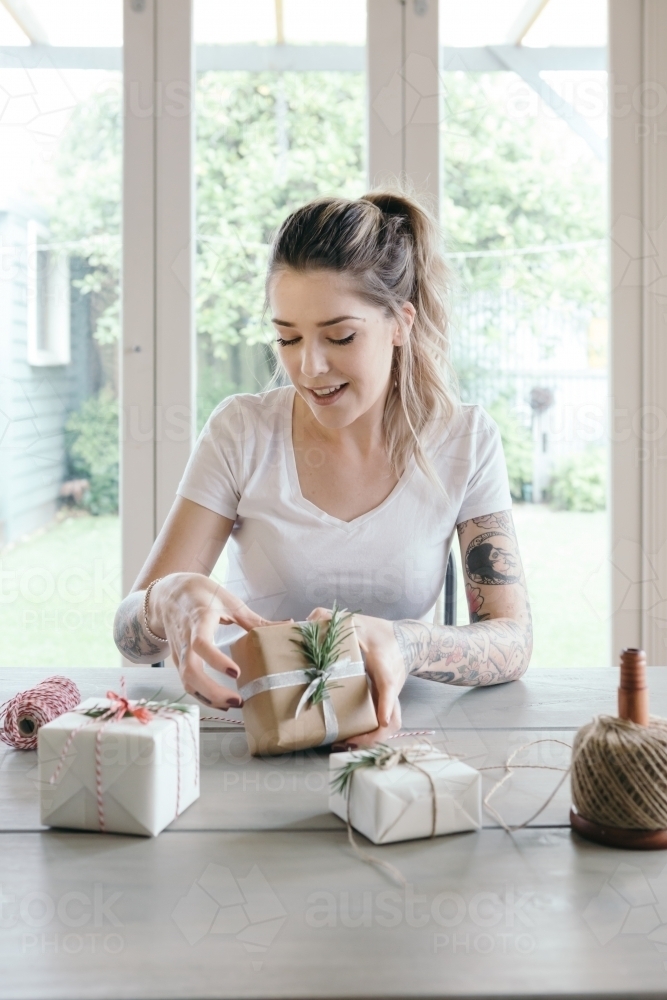 Girl with tattoos wrapping Christmas gifts in a beautiful home - Australian Stock Image