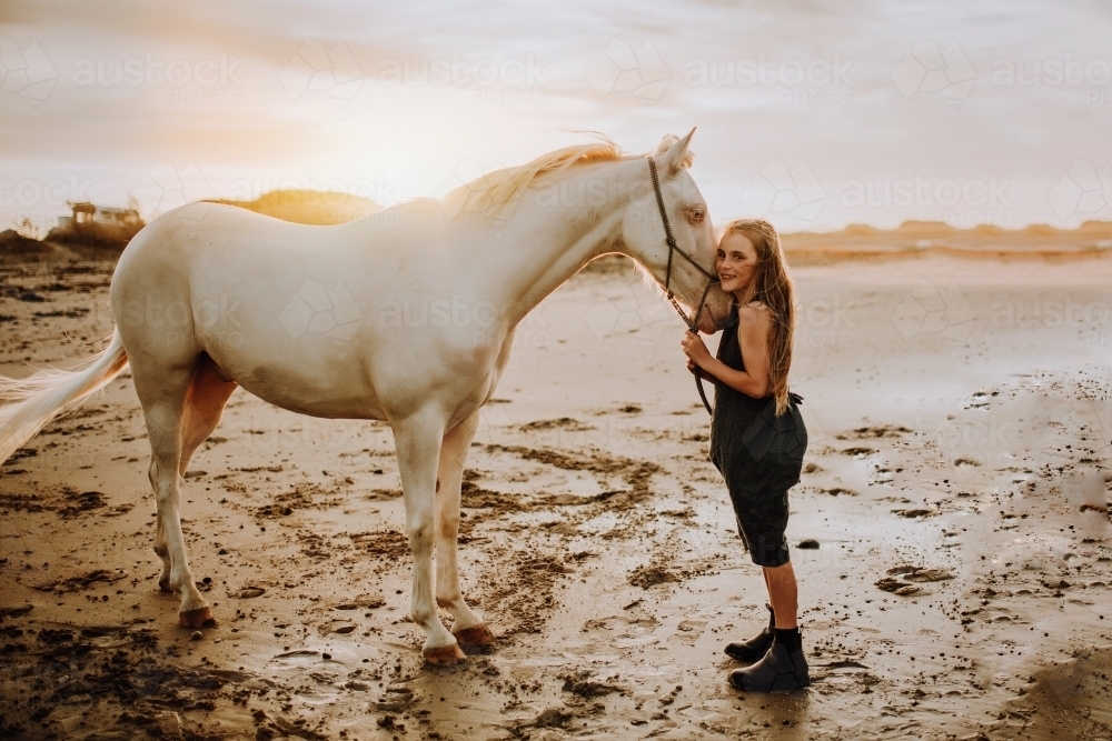 Girl with white horse on the beach at sunset - Australian Stock Image