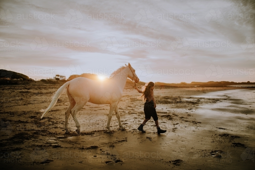 Girl with white horse on the beach at sunset - Australian Stock Image