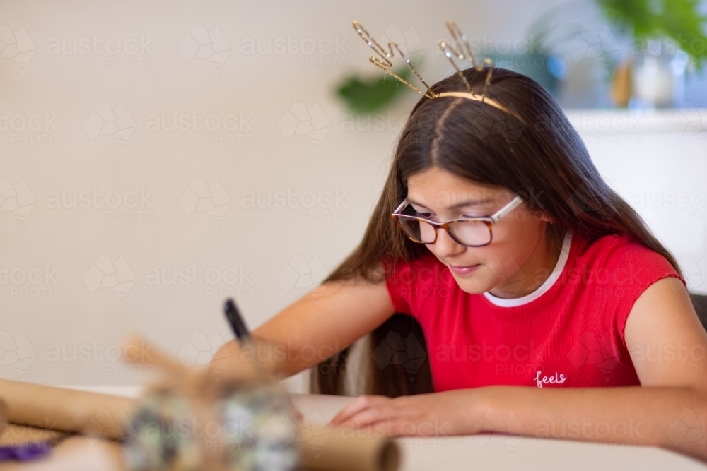 girl wrapping present at Christmas time with antler headband - Australian Stock Image