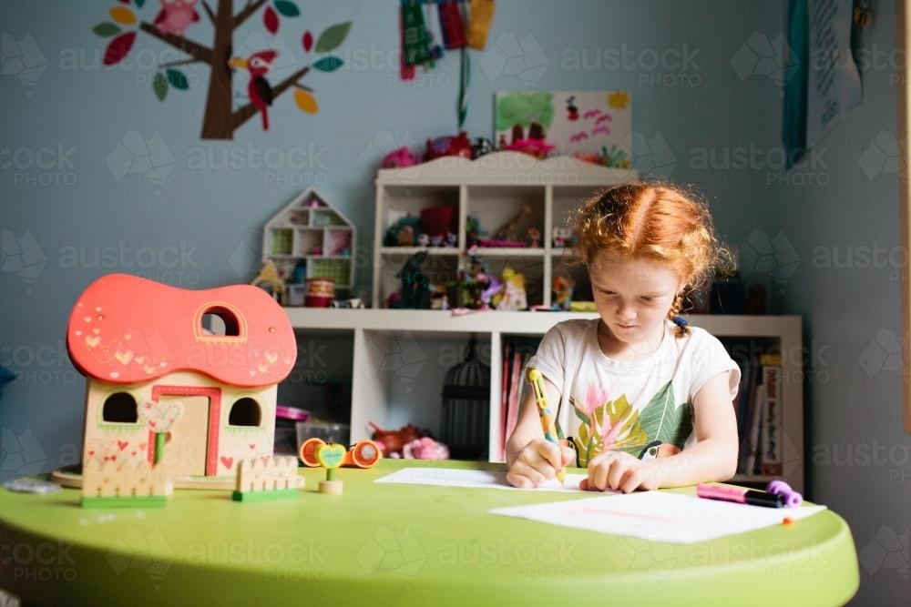 Girl writing at a desk in a bedroom - Australian Stock Image