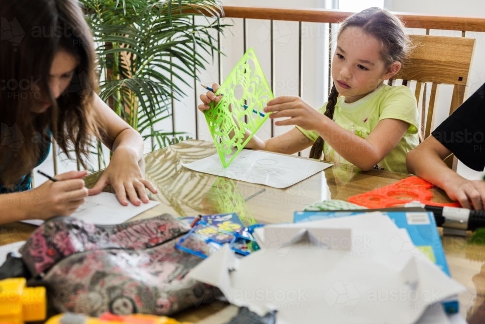 Girls creating artwork, drawing Manga and stencilling at the table - Australian Stock Image