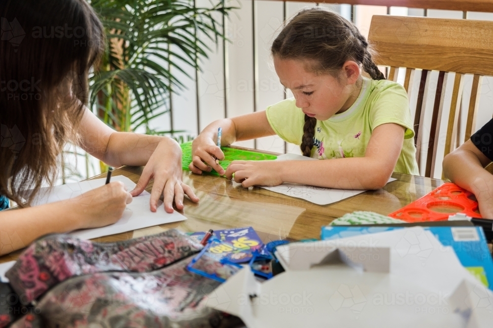 Girls creating artwork, drawing Manga and stencilling at the table - Australian Stock Image