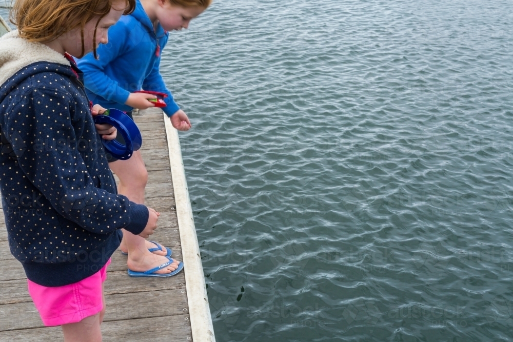 girls fishing with hand reels from a wooden jetty - Australian Stock Image