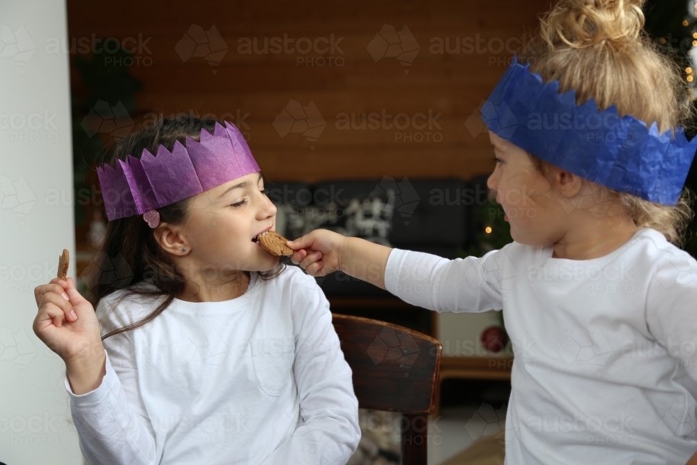 Girls in Christmas hats sharing gingerbread - Australian Stock Image