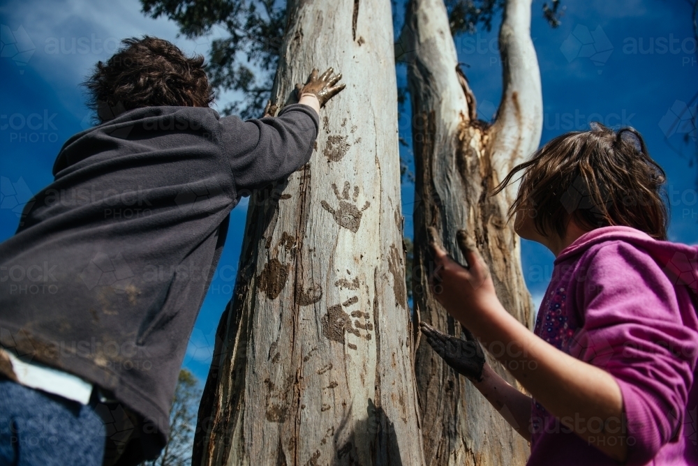Girls making hand prints on eucalypt - Australian Stock Image