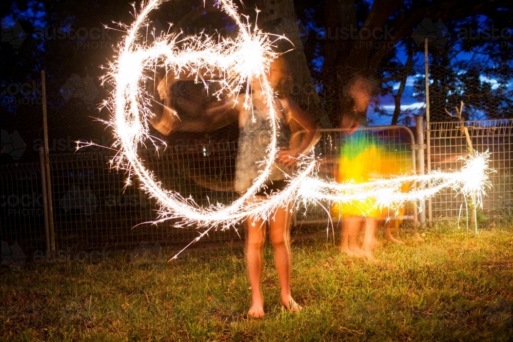 Girls making shapes with sparklers at night - Australian Stock Image