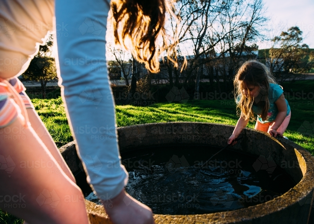 Girls playing in water trough - Australian Stock Image
