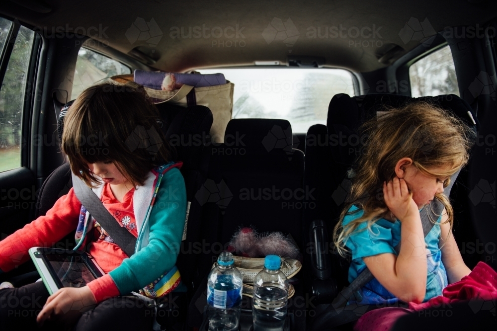 Girls sitting in backseat of car playing - Australian Stock Image