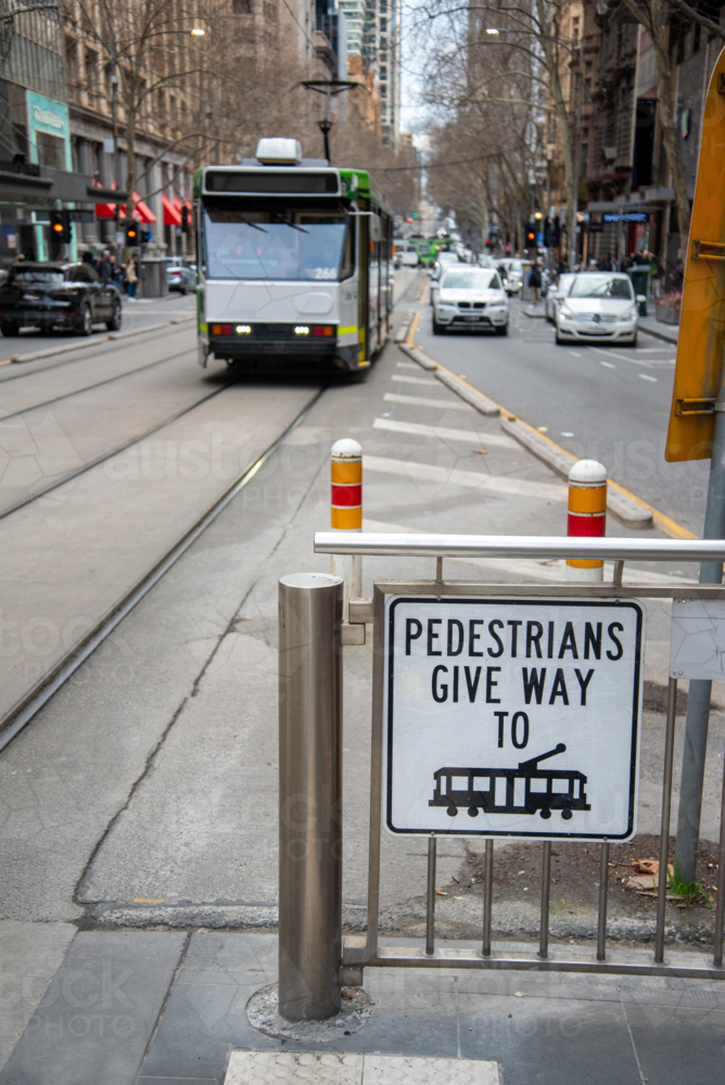 Give way to trams sign with an approaching tram - Australian Stock Image