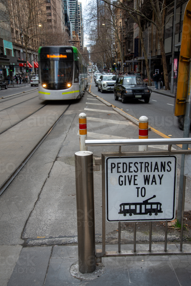 Give way to trams sign with an approaching tram - Australian Stock Image