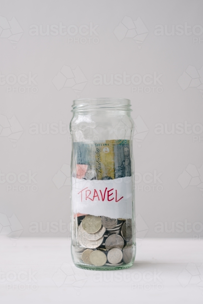 glass jar for saving money, with "travel" label - Australian Stock Image