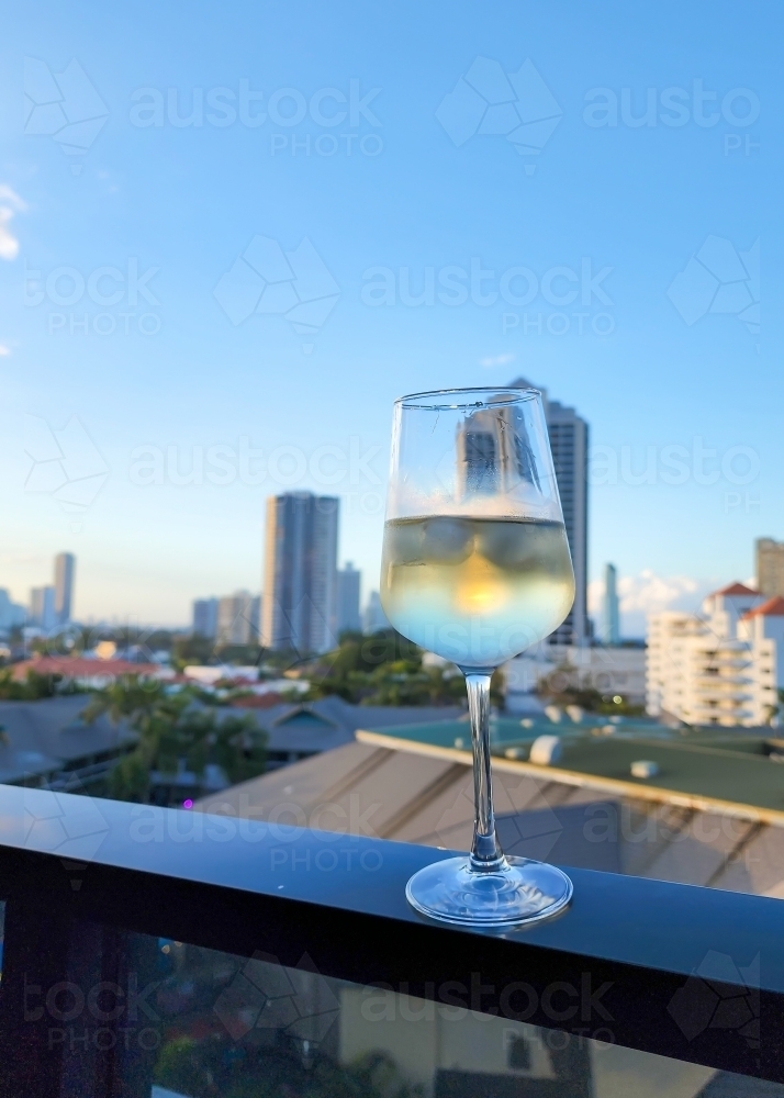 Glass of white wine on hotel balcony with view of the Gold Coast skyline - Australian Stock Image