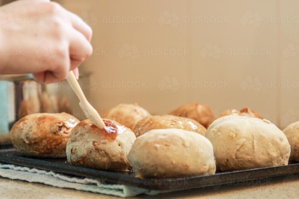 Glazing hot cross buns - Australian Stock Image
