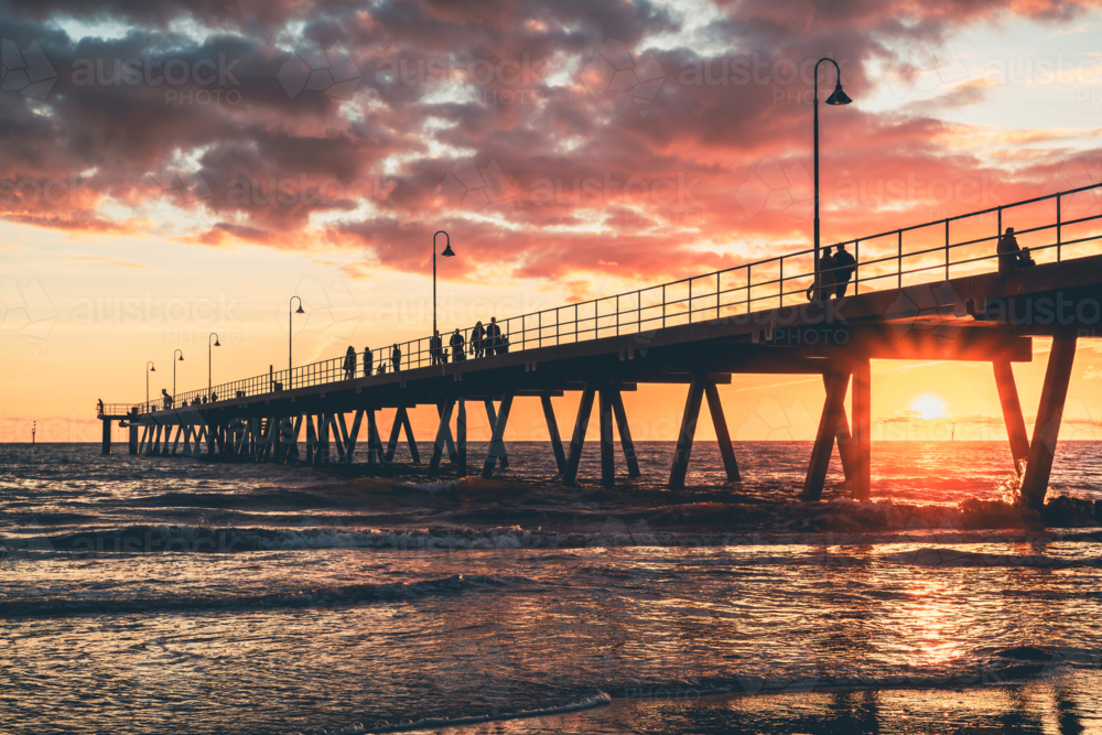 Glenelg Beach jetty with people strolling along at sunset, South Australia - Australian Stock Image