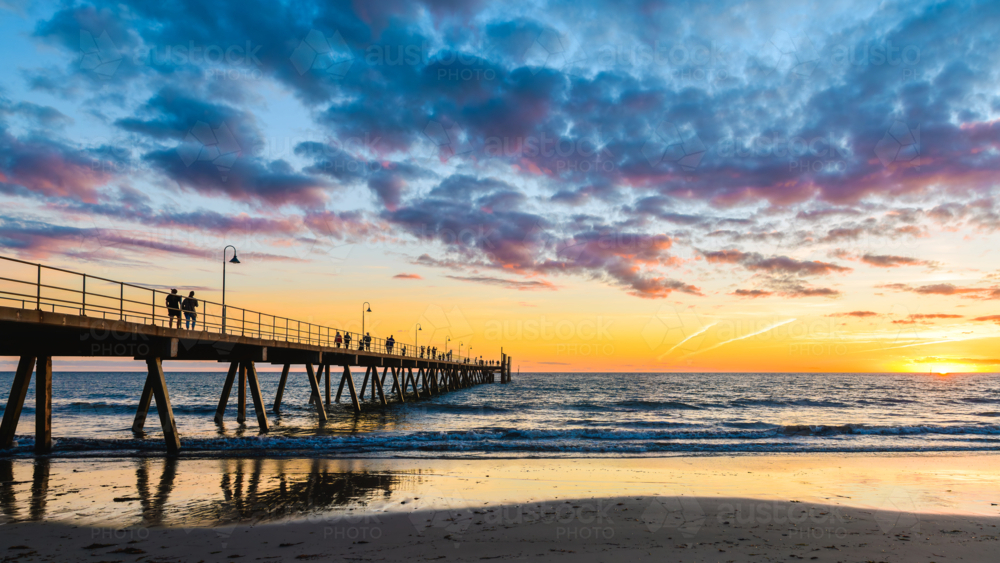 Glenelg Beach pier with walking people silhouettes at sunset at sunset, South Australia - Australian Stock Image