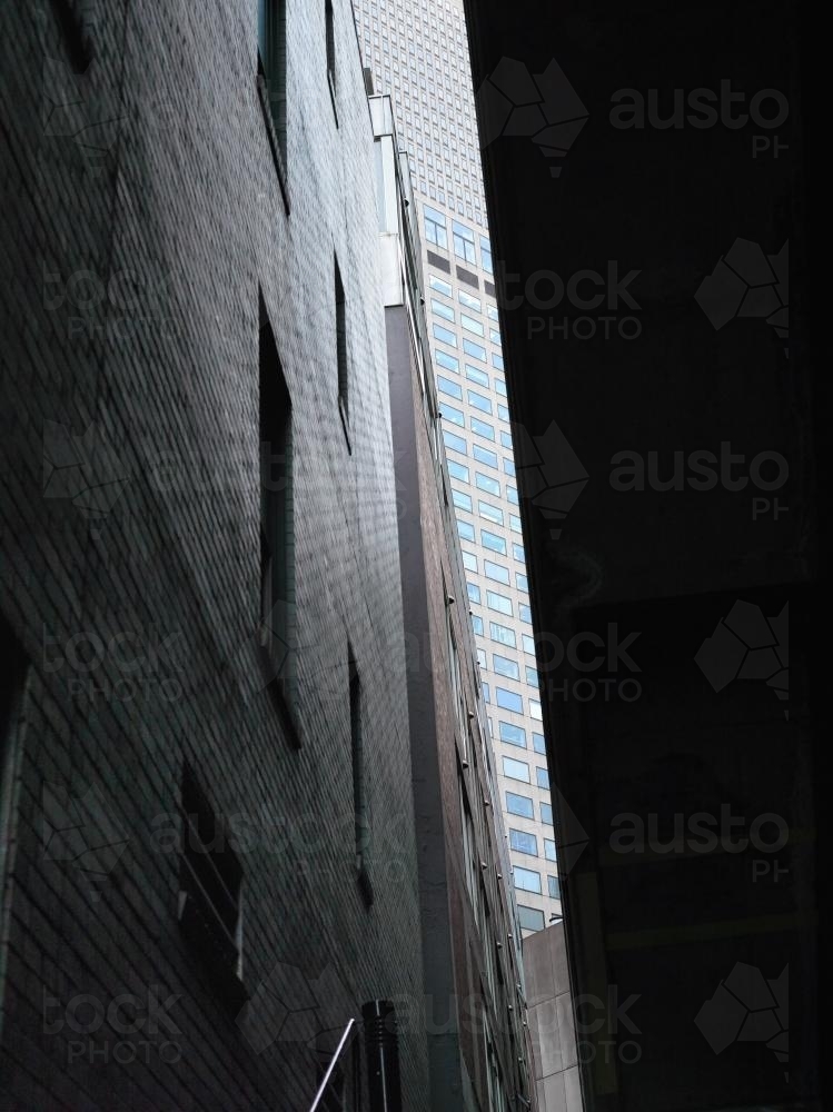Glimpse of modern tower block past old dark laneway building. - Australian Stock Image
