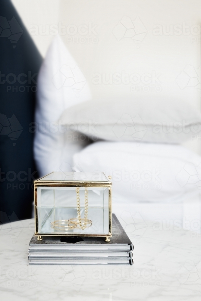 Gold and glass jewellery box and books on bedside table - Australian Stock Image