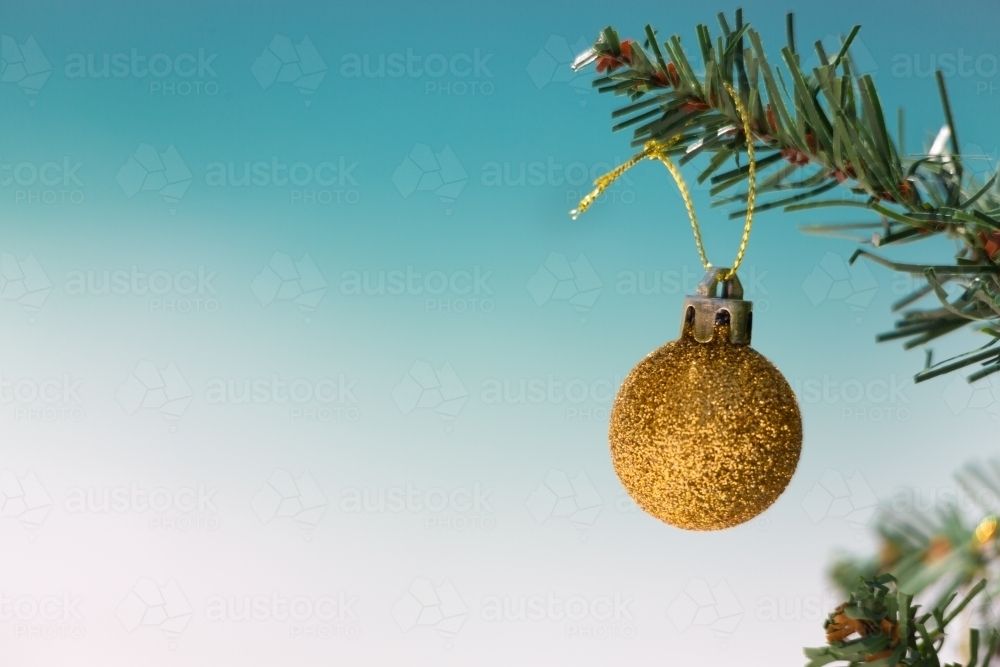 Gold glitter bauble on Christmas tree with beautiful beach background blur. - Australian Stock Image