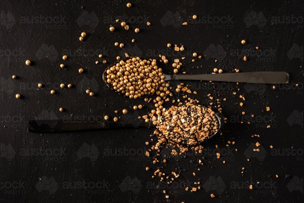 gold salt and pepper on a black background - Australian Stock Image