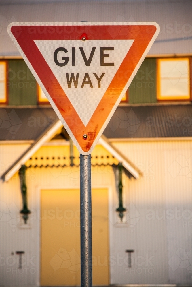 Golden afternoon sun reflecting off Give Way road sign in urban setting - Australian Stock Image