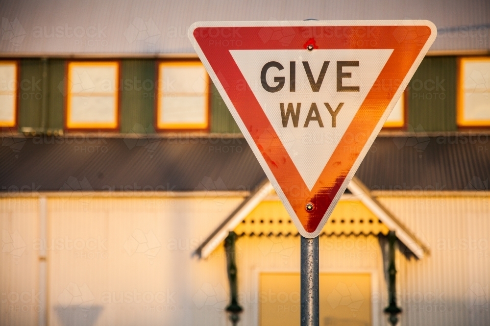 Golden afternoon sun reflecting off Give Way road sign in urban setting - Australian Stock Image