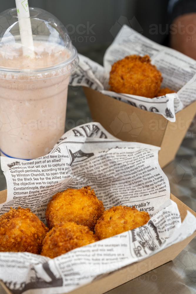 Golden brown croquettes in snack trays lined with faux paper with a cup of milkshake - Australian Stock Image