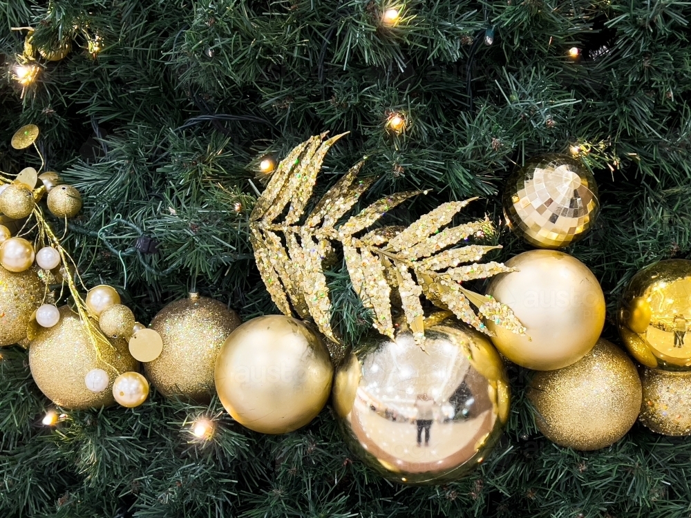 Golden decorations on a christmas tree with reflection and golden leaf - Australian Stock Image