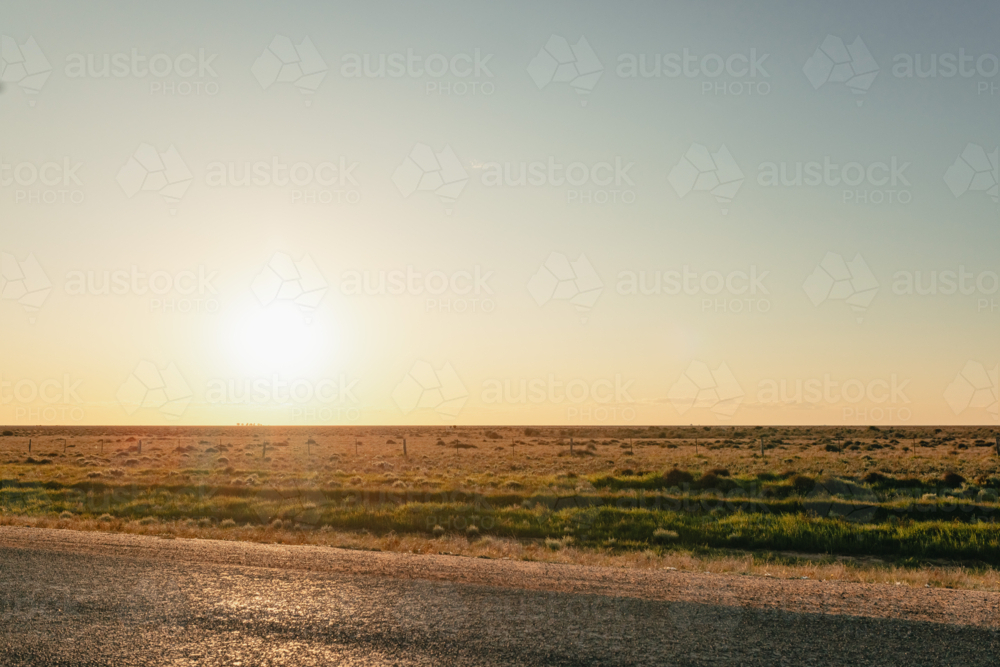 Image of Golden hour sunset over a vast, dry grassland with a distant ...