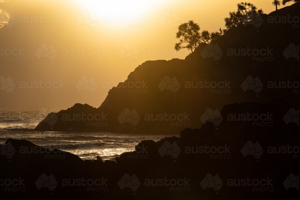 Golden light and silhouetted rocky headland at Cabarita. - Australian Stock Image