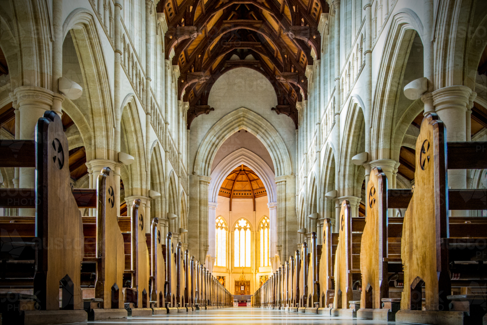 Golden light filling a grand cathedral nave lined with soaring arches. - Australian Stock Image