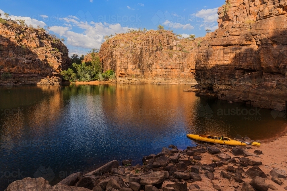 Golden light on pool of water in Nitmiluk Gorge with canoe - Australian Stock Image