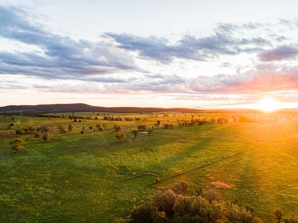 Golden rays of sunlight over green farmland paddock - Australian Stock Image