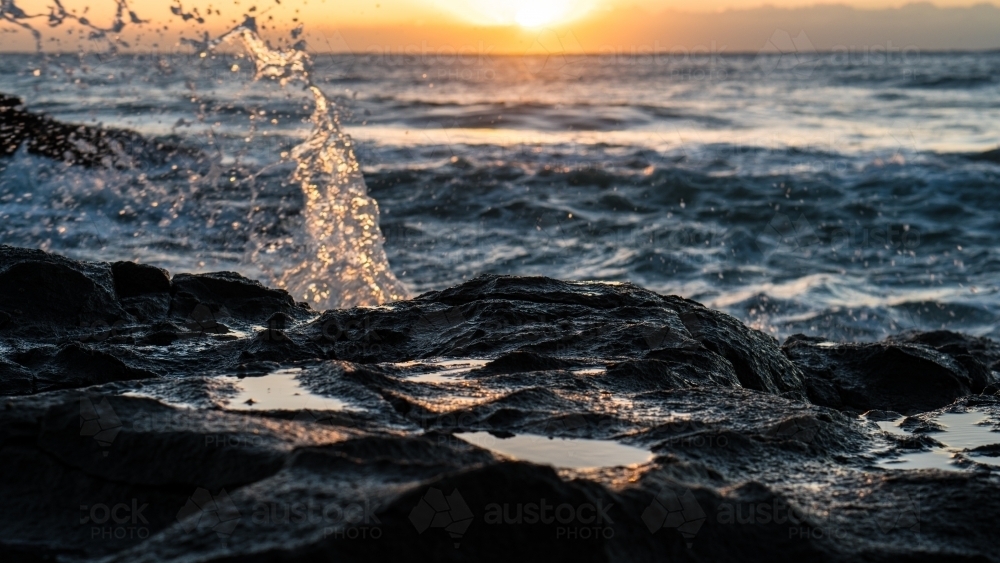 Golden splash off rocks at sunrise - Australian Stock Image
