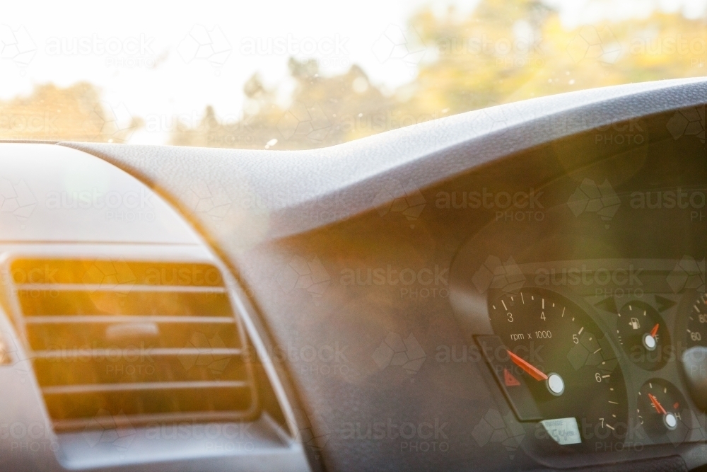 Golden sun flare over air con vent and speedometer of car - Australian Stock Image