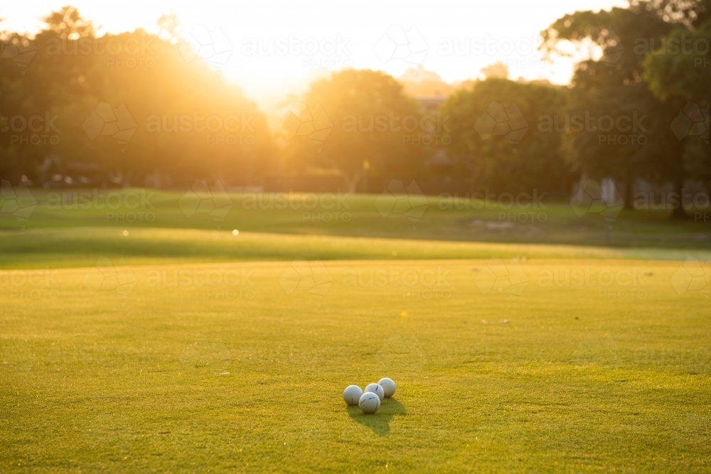 Golf balls on the green at sunset - Australian Stock Image