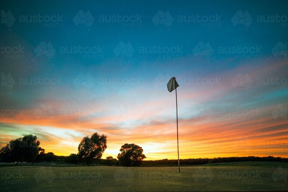 Golf hole flag in front of sunset coloured sky. - Australian Stock Image