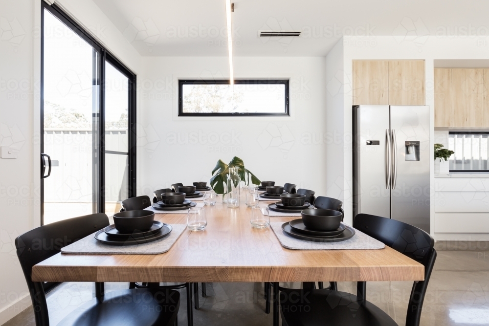 Gorgeous dinner setting of black crockery on an oak table in a modern home - Australian Stock Image