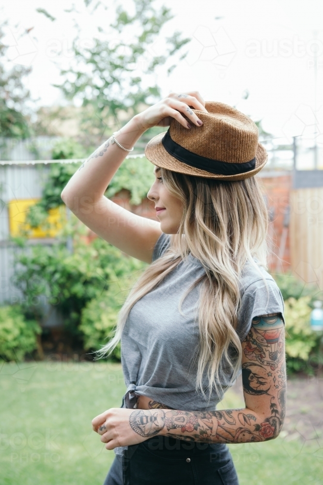 Gorgeous fashionable female posing with a hat in the garden - Australian Stock Image