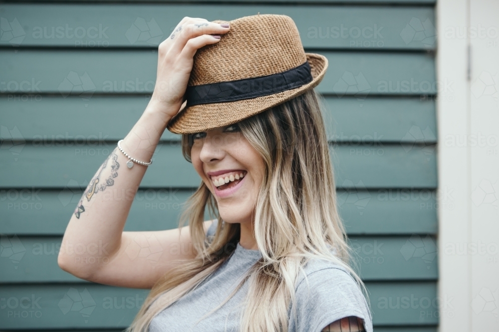 Gorgeous fashionable girl playfully putting on a hat - Australian Stock Image