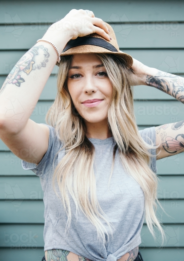Gorgeous girl with long blonde hair putting on a summer hat - Australian Stock Image