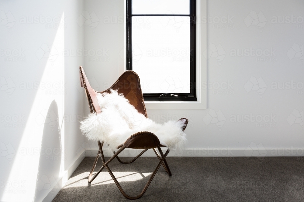 Gorgeous leather occasional chair with scandi style sheepskin - Australian Stock Image