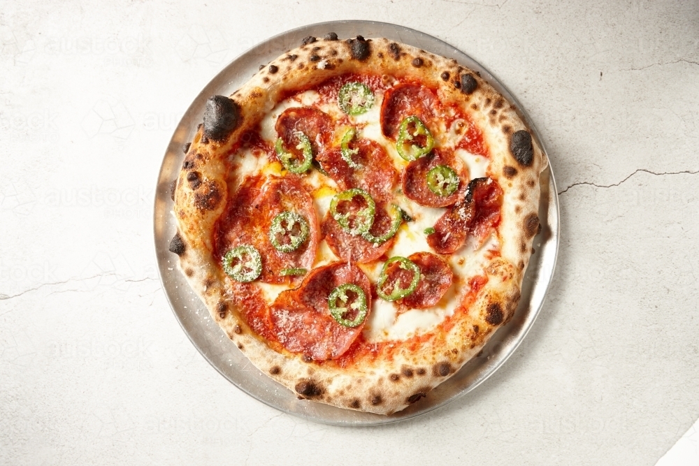 Gourmet wood fired salami pizza on table - Australian Stock Image