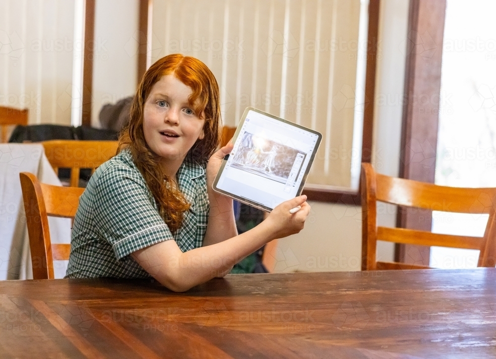 grainy image of schoolgirl holding up digital tablet to show what she has been sketching - Australian Stock Image